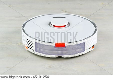 Robot Vacuum Cleaner On The Wooden Floor Cleaning The Room. Smart Cleaning And Washing Technology. A