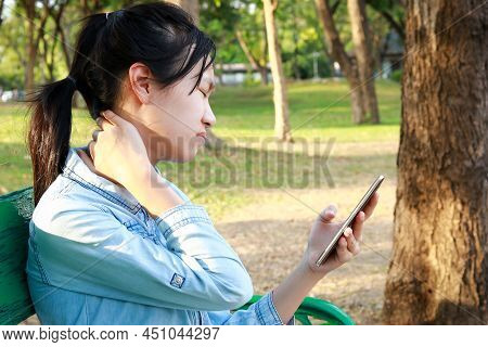 Asian Child Girl Has Neck Pain,massage Her Neck,bending Head While Playing The Mobile Phone For A Lo