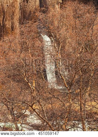 Through The Autumn Trees One Can See A Powerful Stream Of A Waterfall Flowing In The Rocks Of The Ca