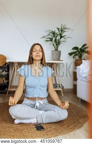 Trendy Young Woman Wearing Earphones Meditating Online And Listening Music On Smartphone Player App 
