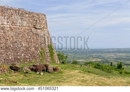 The Ancient Fortress Of Radicofani Wall With bindweed And Distant Hill Horizon. Tuscany, Italy