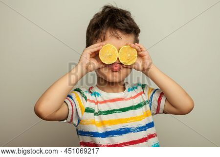 A Funny Emotional Boy, A Child With Yellow Fresh Lemons In His Hands Closes His Eyes With Lemons And