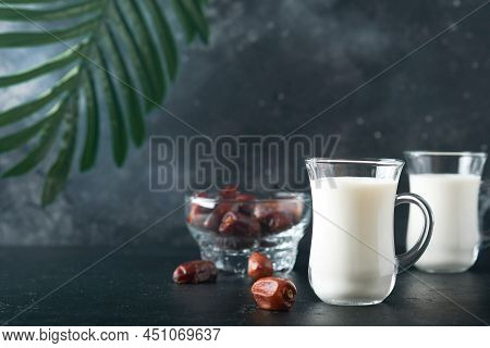 Ramadan Kareem Food And Drinks. Plate Of Dates, Glass Of Milk And Date Palm Branch On Black Backgrou