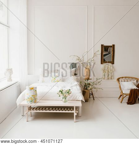 A Bed In The Bedroom With White Linens, Spring Yellow Flowers In A Vase On The Bedside Table In The 