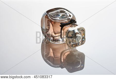 Eau de parfum Givenchy Very Irresistible Rose Damascena lies on a white mirror background. Reflection, gradient.