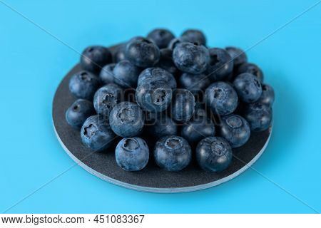 Fresh Blueberries On A Gray Round Ceramic Board On A Blue Background. Horizontal.