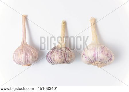 Three Fresh Garlic Lie On A White Background. Close Up Top View.
