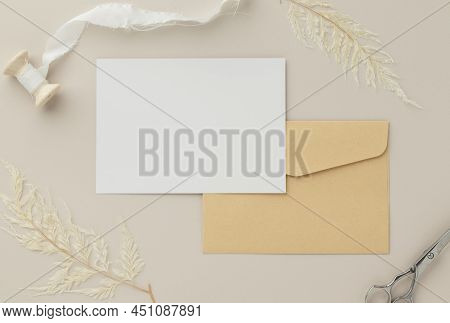 Blank Greeting Card Invitation Mockup 5x7 On Brown Envelope With Dried Flowers On Beige Background, 