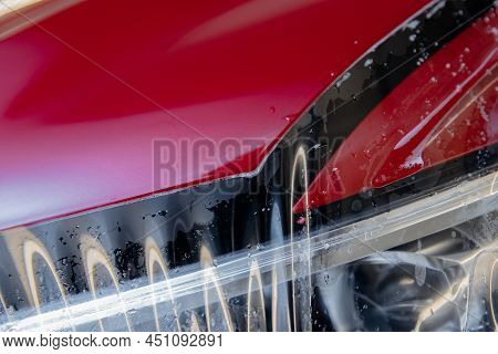 Process Of Pasting Hood Of Red Car With Protective Vinyl Film From Gravel Chips And Scratches. Trans