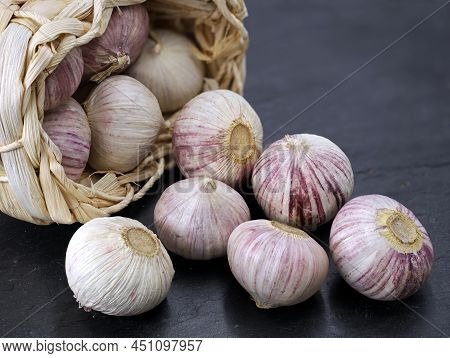 Solo Garlic Or Chinese Garlic, Allium Sativum In A Straw Basket On A Black Slate Background
