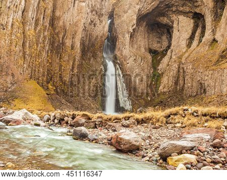 A High Powerful And Smooth Stream Of A Waterfall Flows In Steep Rocks Covered With Moss, Falling Int