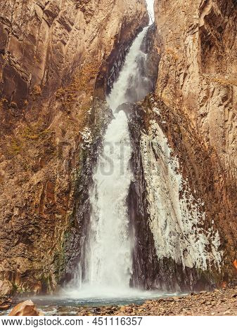 A Huge Powerful Waterfall Flows Down Between The Steep Cliffs Of The Caucasian Highlands.