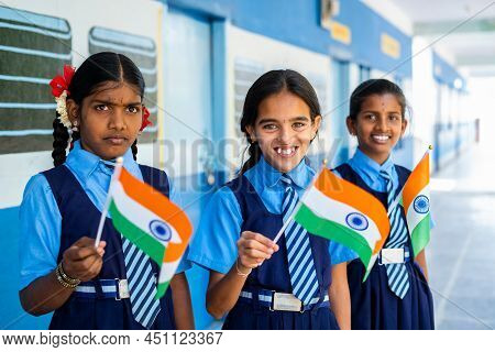 Smiling Girl Kis In Unifrom Waving Indian Falg By Looking At Camera At School Corridor - Concept Of 