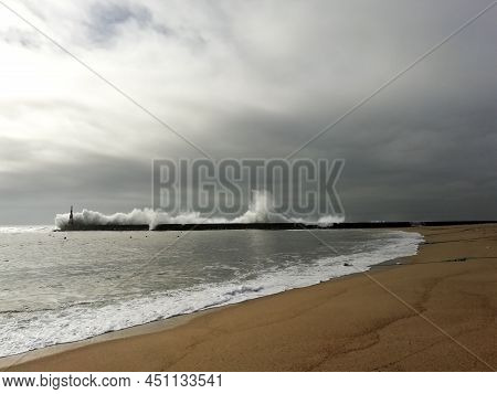 Giant Waves Breaking On The Breakwater And The Lighthouse On Aguda Beach, Miramar, Arcozelos Town