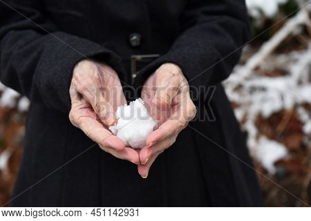Elderly Woman, 100 Years Old, Is Still Fiesty And Game.  She Is Making A Snowball In Her Aging Hands