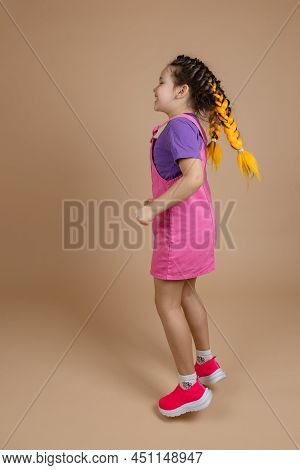 Enthusiastic Blissful Female Child With Two Kanekalon Pigtails Of Yellow Color Having Fun Jumping Dr