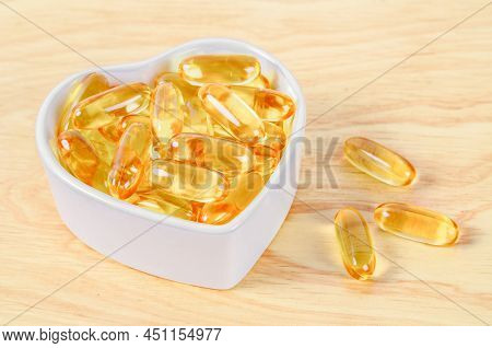 Cod Liver Oil Capsules In White Cup On Wooden Flloor.