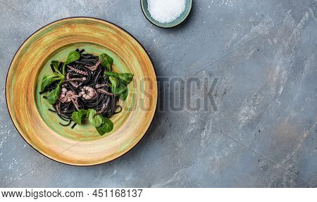 Squid Ink Spaghetti With Seafood Octopus, Mussels And Shrimps On Dark Background. Pasta Of Durum Whe