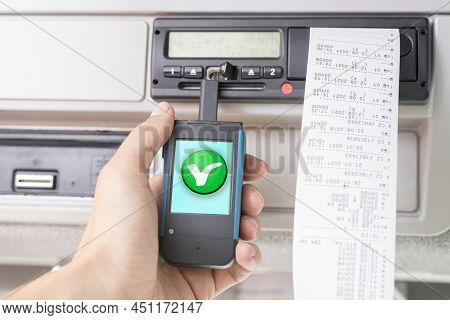 Driver Holding A Digital Tachograph Reader With A Green Ok Check Mark. Tachograph Download. Control.