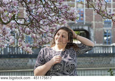 Portrait Of A Beautiful Plump Caucasian Confident Woman In Magnolia Flowers