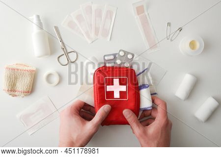 Hands Picking Up First Aid Travel Kit Bag For Emergency On White Table. Horizontal Composition. Top 