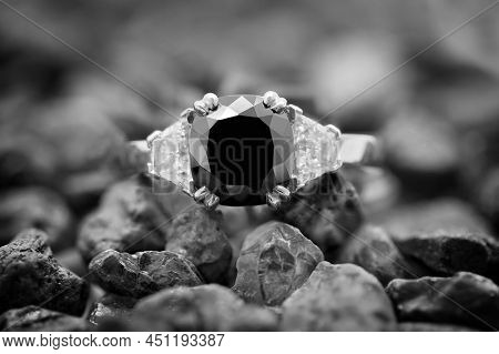 A Black Diamond Ring With Trillion Cut White Diamonds Resting On A Pile Of Raw Gemstones. Monotone I