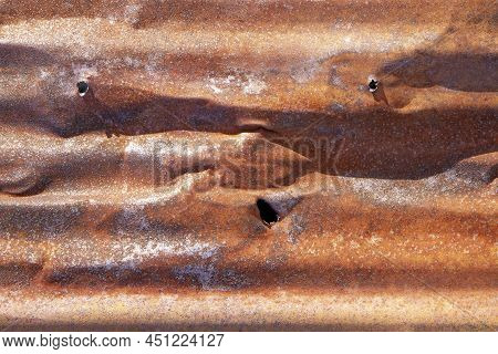 Brown Abstract Background With Silver Red Hues. A Weathered, Rust-eaten, Crumpled, Perforated Textur
