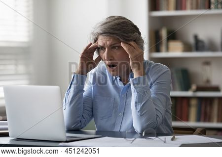 Aged Businesswoman Staring At Laptop Feels Shocked By Bad News