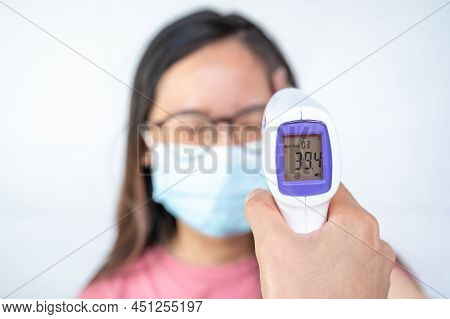 Someone Hand Using Infrared Thermometer Gun To Measuring Woman Temperature And The Monitor Show High
