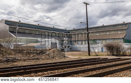 Braddock, Pennsylvania, Usa March 19, 2022 An Old Warehouse Next To Train Tracks And A Crossing On A