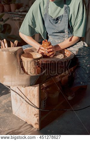 Potter Working Manually On Pottery Wheel In Workroom