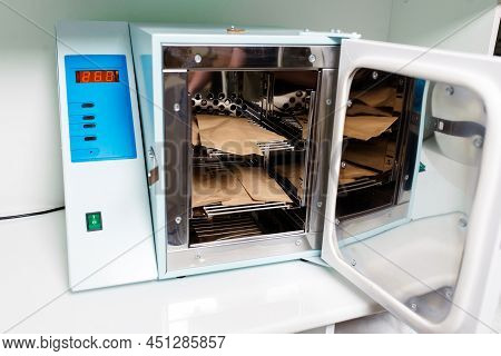 Beautician In Protective Gloves Close The Door Of The Machine For Disinfection Of Tools Before The D