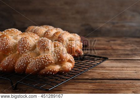 Closeup View Of Homemade Braided Breads With Sesame Seeds On Wooden Table, Space For Text. Tradition