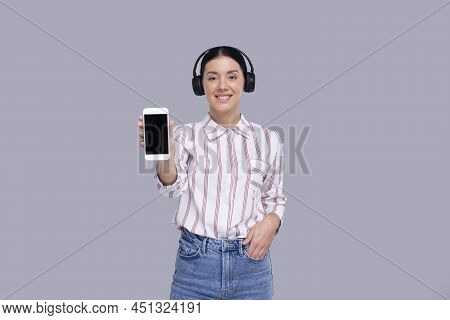 Girl Showing Phone Wearing Headphones Standing Isolated. Commecial, Shopping, Advertisment Concept