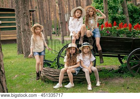 Group Portrait Of Preteen Girls Near Old Wooden Cart Used As Flower Bed In Park