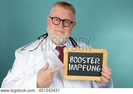 Doctor With Eyeglasses Holding Blank Chalkboard On Blue Background Tells You Get Booster Impfung.