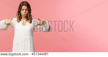 Gloomy, Jealous And Upset Cute Blond European Woman In White Trendy Spring Dress, Sulking As Pointin