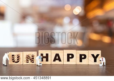 Worker Team On Unhappy Word In Wooden Alphabet Letters With Prefix Un Crossed Out, Leaving The Word 