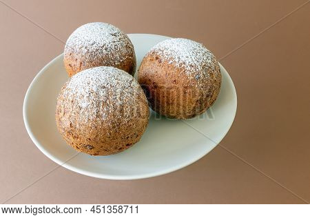 Three Lithuanian Large Donuts Sprinkled With Powdered Sugar On A Brown Background