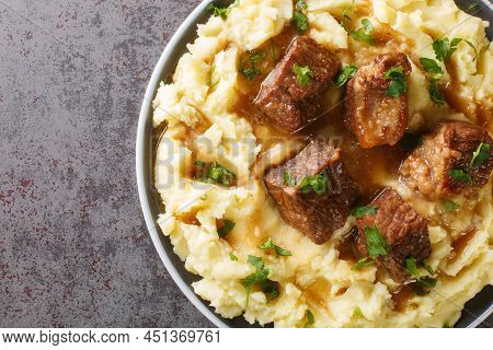 Slowly Stewed Beef With Wine And Vinegar Garnished With Mashed Potatoes Close-up In A Plate On The T
