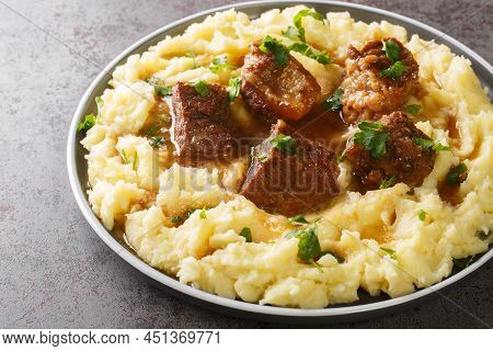 Slowly Stewed Beef With Wine And Vinegar Garnished With Mashed Potatoes Close-up In A Plate On The T