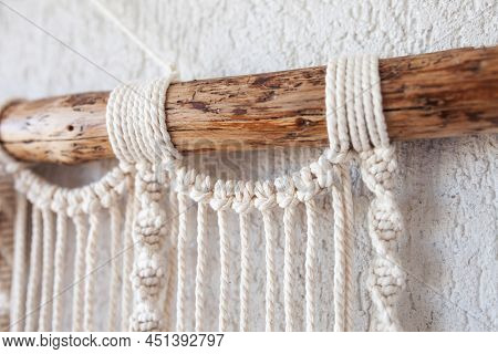 Handmade Macrame Wallhanging. 100% Cotton Wall Decoration With Wooden Stick Hanging On A White Wall.