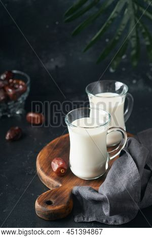 Ramadan Kareem Food And Drinks. Plate Of Dates, Glass Of Milk And Date Palm Branch On Black Backgrou