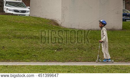 Toronto, Ontario, Canada, August 2013 - Male Kid Of African Ethnicity Riding A Scooter On The Sidewa