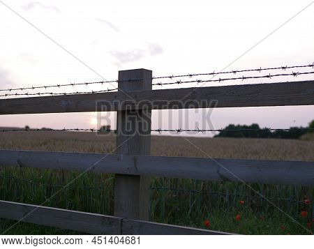 Sunseting In Background And Barbed Wire Fence Silhouette