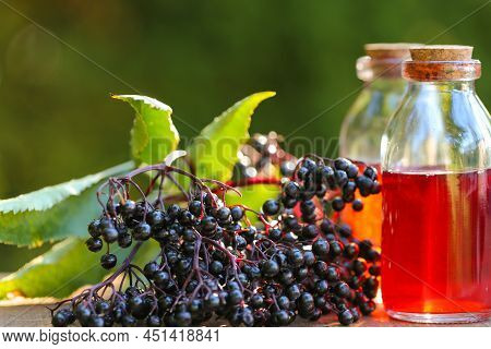 Elderberry Syrup.sambucus Syrup In A Glass Bottle And Bunches Of Elderberries On A Wooden Table In T