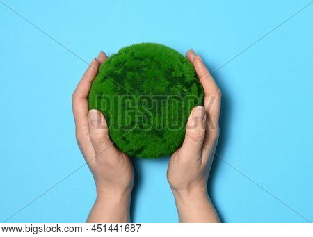 Hands with a green planet on light blue backgroundbackground