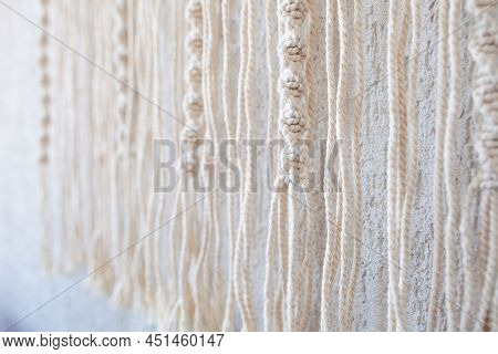 Handmade Macrame Wallhanging. 100% Cotton Wall Decoration With Wooden Stick Hanging On A White Wall.
