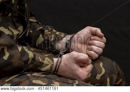 A Military Man In Camouflage Is Handcuffed On A Dark Background. Concept: War Criminal, Prisoner Of 