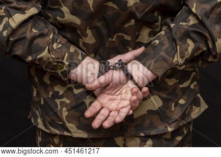 A Military Man In Camouflage Is Handcuffed On A Dark Background. Concept: War Criminal, Prisoner Of 